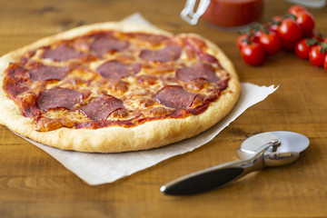 Rustic pizza with salami, mozzarella, olives and basil.