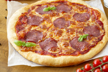 Rustic pizza with salami, mozzarella, olives and basil.