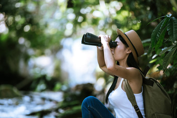 Woman with Binoculars and Telescope in Rain Forest.Travel concept. Hiking at summertime.