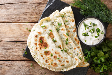 Azerbaijani food: flatbread qutab with greens and yogurt close-up. horizontal top view