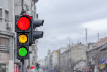 Red light with yellow and green semaphore city urban blury background
