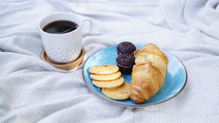 croissants, biscuits and coffee on a picnic overlay