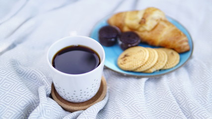 croissants, biscuits and coffee on a picnic overlay