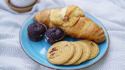 croissants, biscuits and coffee on a picnic overlay