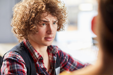 Young businessman with curly hair talking to his colleague at start-up meeting