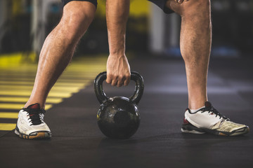 Close up male hands holding hard kettlebell. He standing in keep-fit studio