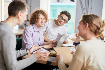 Group of young professionals in casualwear gathered for discussion of new ideas at start-up meeting