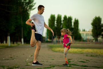 Athletic young father and little daughter do exercises in stadium. Healthy lifestyle