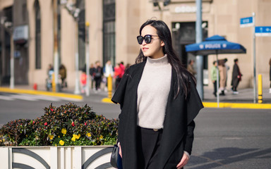 Outdoor portrait of young beautiful fashionable playful Chinese lady in black smiling at camera with sunglasses in Sunny day. Female fashion. City lifestyle. Travel concept.