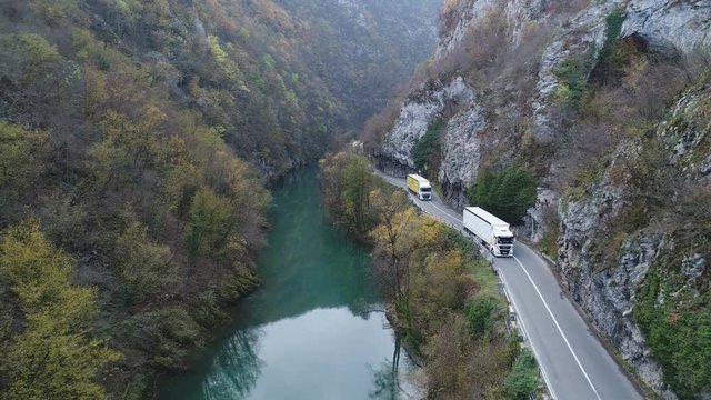 Aerial view of trucks driving past rock formations in narrow gorge in mountainous region Bosnia and Herzegovina