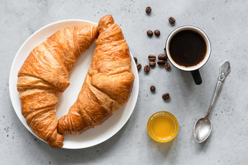 Croissants, coffee and honey on concrete background. Top view. Continental breakfast, coffee break or lunch concept
