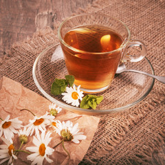 Cup of medicinal herbal chamomile mint tea on a wooden desk. Rustic style background.