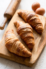 Freshly baked croissants on wooden board. Closeup view