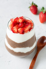 Chia pudding with chocolate and strawberries in a glass on concrete background