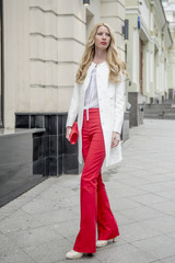 Fashionable young blonde in a spring fashionable suit and with a shopping bag in the center of Moscow
