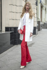 Fashionable young blonde in a spring fashionable suit and with a shopping bag in the center of Moscow
