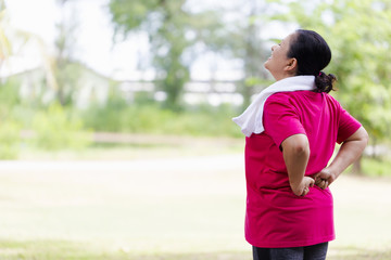 Senior Asian woman suffering from backache while exercise on park outdoors. Mature woman with...