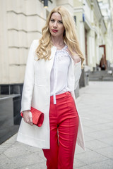 Fashionable young blonde in a spring fashionable suit and with a shopping bag in the center of Moscow
