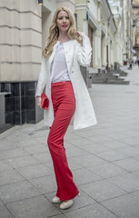 Fashionable young blonde in a spring fashionable suit and with a shopping bag in the center of Moscow
