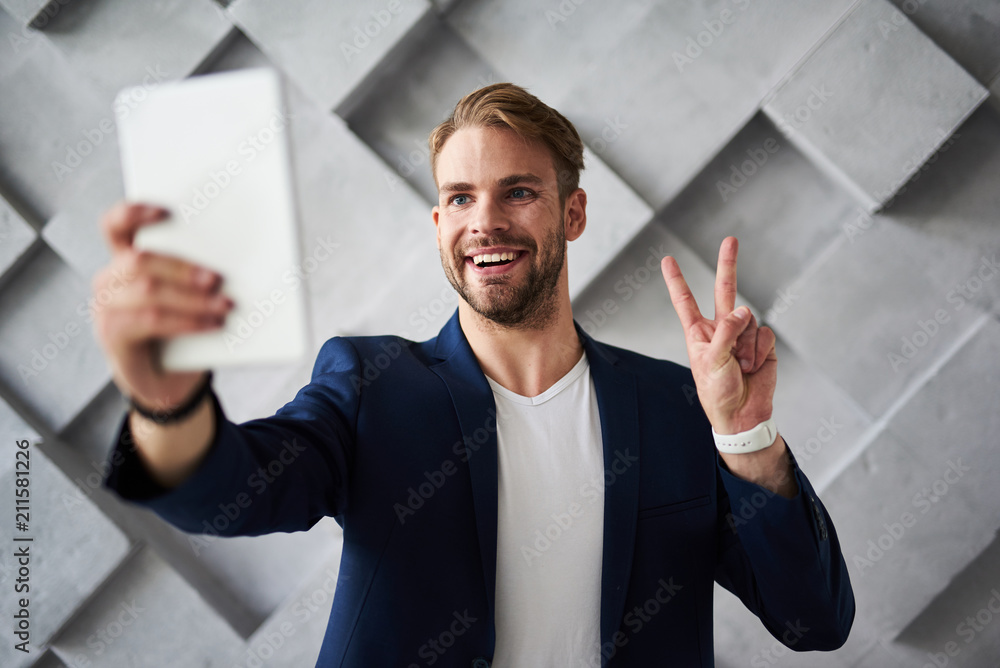 Poster hello. waist up portrait of good looking businessman communicating on tablet with joy. he is holding