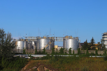 Panorama of the oil refinery. Metal structures and buildings in the rays of sunlight against a background of dark thunderclouds.Power industry. Ecology of the environment of human habitation. 