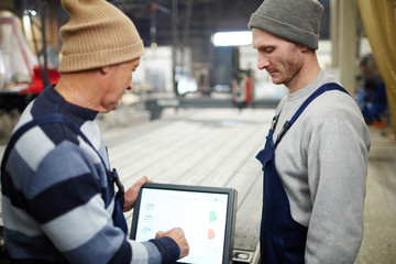 Young and senior colleagues looking for technical data while working in shipyard