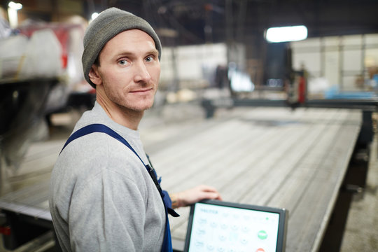 Young worker of shipyard in workwear looking at camera while carrying out technical work