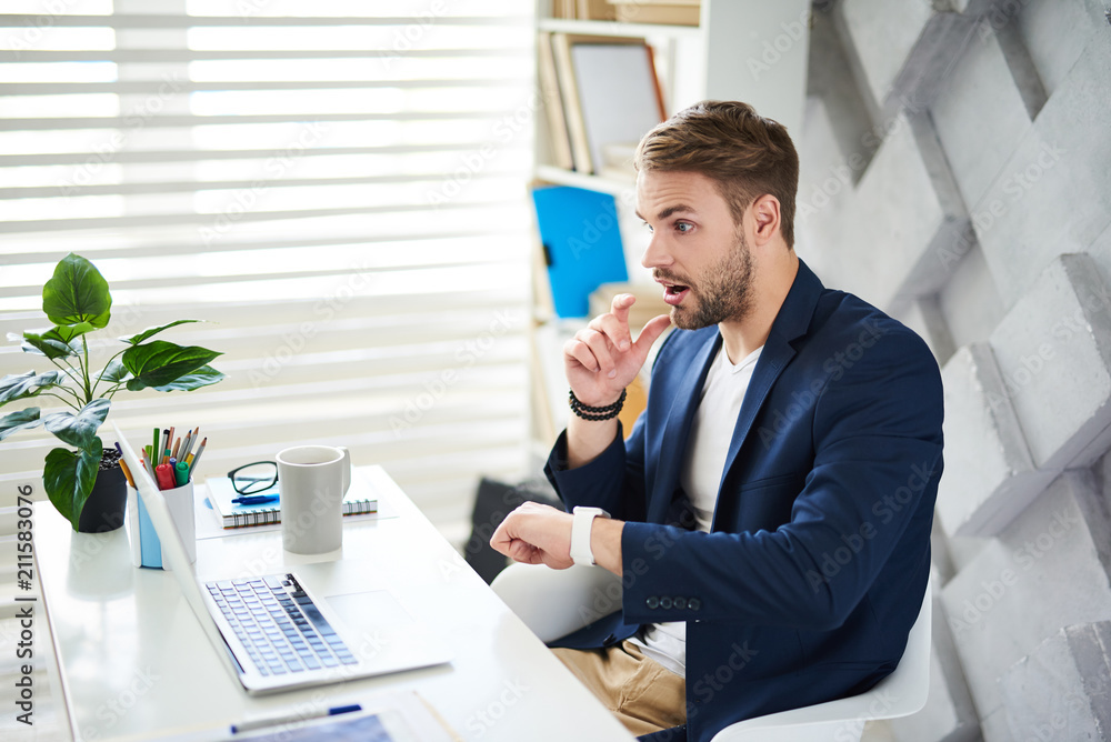 Poster side view profile of amazed businessman sitting at desktop. he is looking at screen and checking tim