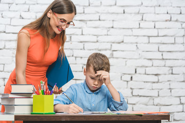 Student boy doing difficult work in school supervised by his teacher