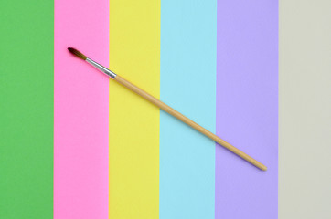 A new paint brush lie on texture background of fashion pastel pink, blue, green, yellow, violet and...