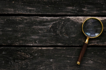 Magnifying glass on wooden table background.
