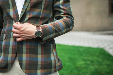 Close up of male arm buttoning his fashionable jacket. Man is standing outdoor with watch on wrist. Copy space 