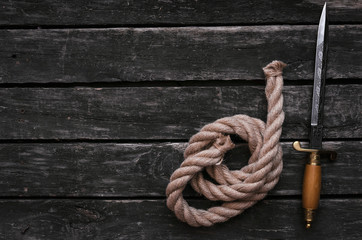 Dagger blade, moorings rope and compass on vintage wooden background with copy space. Adventurer...