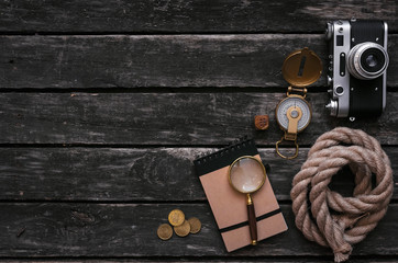 Notepad, magnifier, compass, moorings rope and vintage film photo camera on wooden table background...