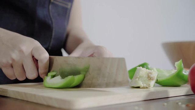 Close up of chief woman making salad healthy food and chopping bell pepper on cutting board.