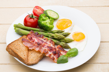 Fried eggs with bacon on the wooden table.