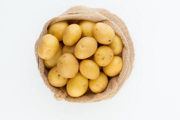 Sack of fresh raw potatoes on wooden background, top view