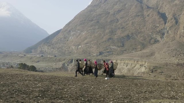 Local farmers carry heavy wicker baskets on the heads in Nepal. Manaslu area.