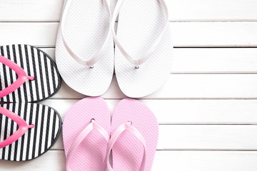 Summer background. Flip-flops on a white wooden background. White, pink, striped beach slippers on...