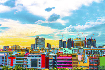 Bird view over cityscape and construction site including several cranes working on a building complex, with sun and clouds in the morning.Copy space.Bangkok.Pastel tone