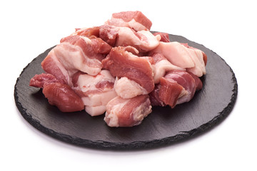 Pieces of fresh pork meat on stone plate, isolated on white background. Close-up.