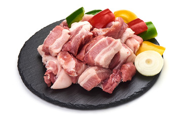 Pieces of fresh pork meat sliced vegetables on stone plate, isolated on white background. Close-up.