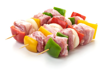 Skewers with pieces of raw meat, red, yellow and green bell pepper, seasoned with coarse salt and olive oil, isolated on white background. Close-up.