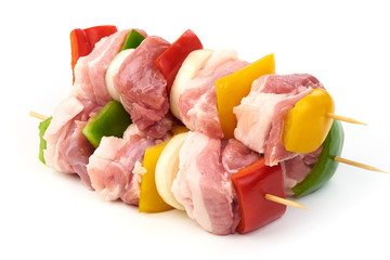 Skewers with pieces of raw meat, red, yellow and green bell pepper, seasoned with coarse salt and...