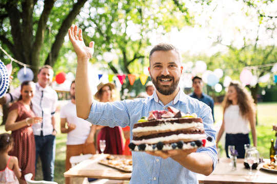 Man with a cake on a family celebration or a garden party outside.