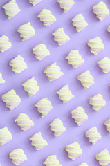 Colorful marshmallow laid out on violet paper background. pastel creative textured pattern. minimal