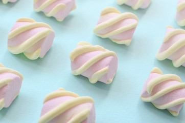 Colorful marshmallow laid out on blue paper background. pastel creative textured pattern. Perspective macro shot