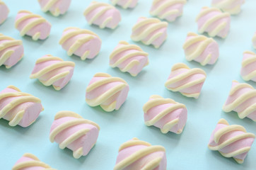 Colorful marshmallow laid out on blue paper background. pastel creative textured pattern. Perspective macro shot