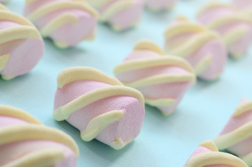 Colorful marshmallow laid out on blue paper background. pastel creative textured pattern. Perspective macro shot