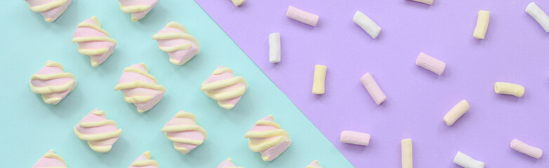 Colorful marshmallow laid out on violet and blue paper background. pastel creative textured...
